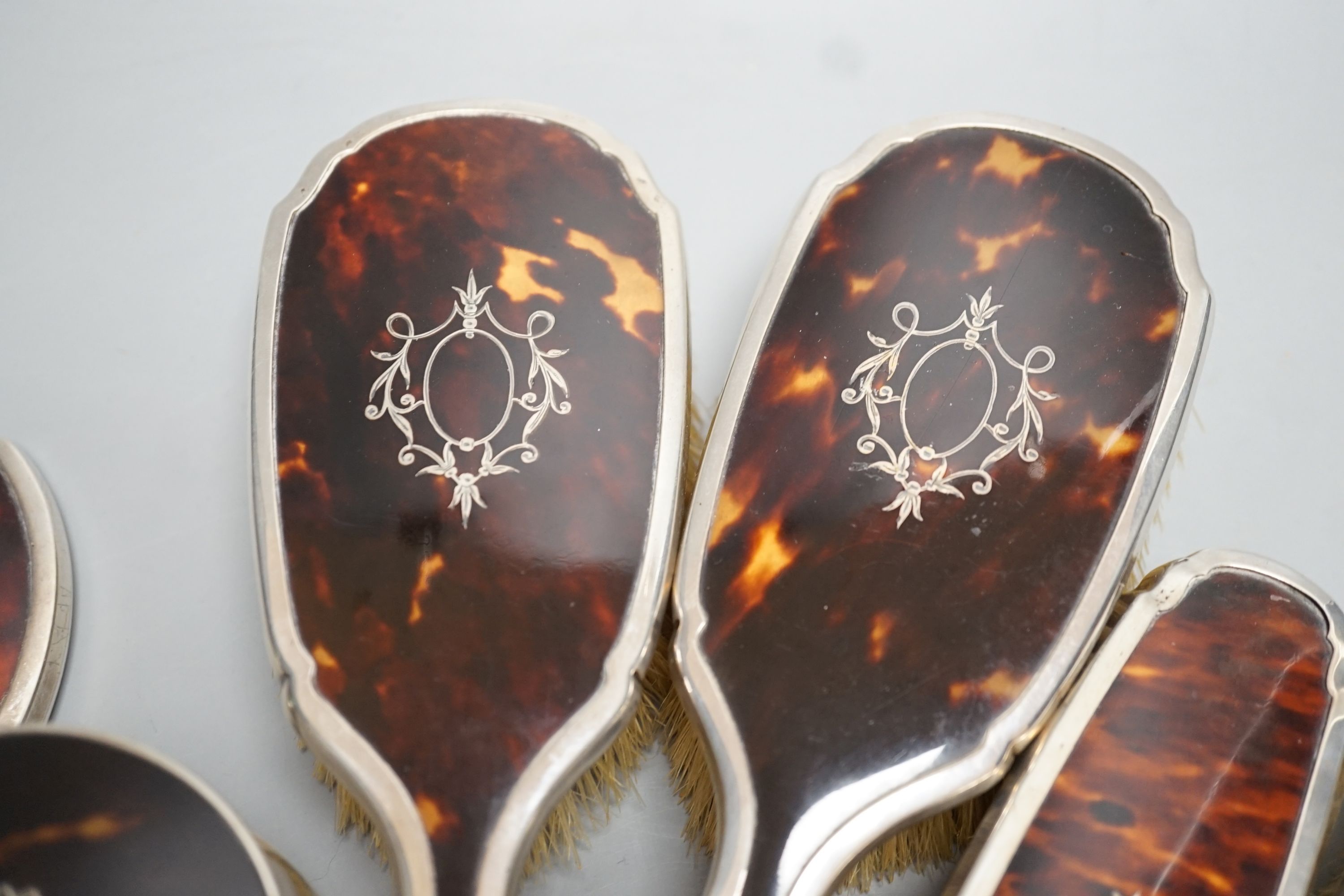 A George V silver and tortoiseshell mounted mirror and brush set, Birmingham, 1928 and a similar powder jar.